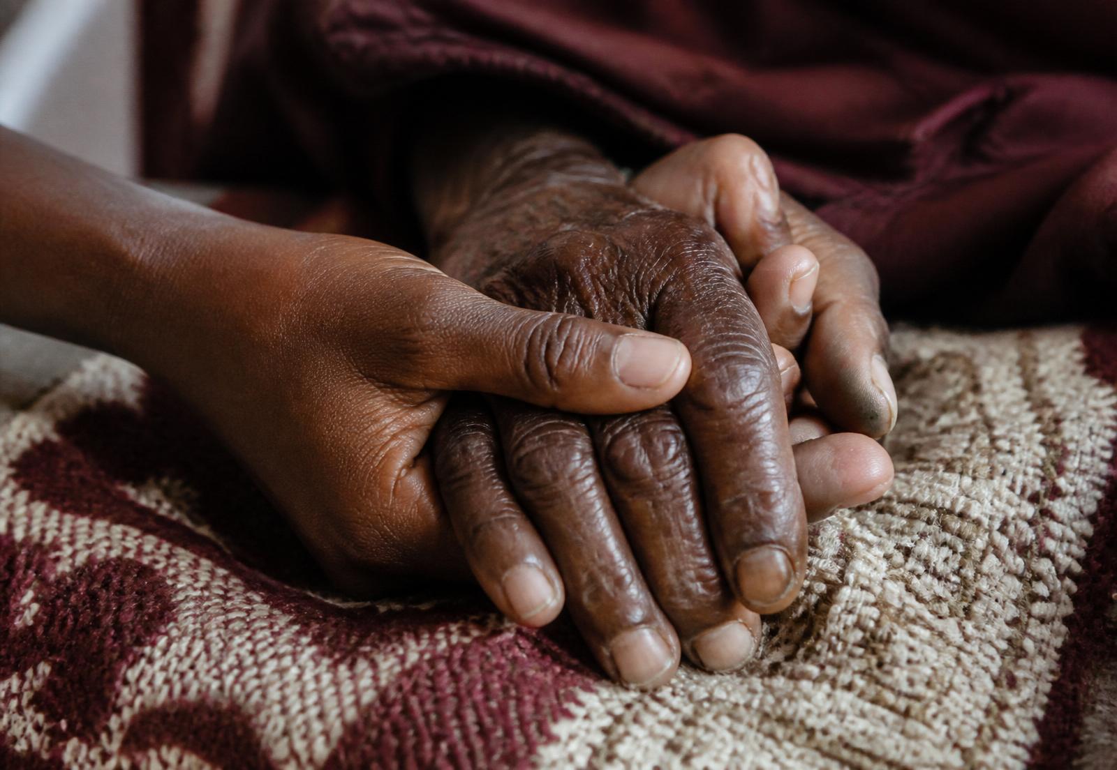 Two hands — young and old — resting intertwined
