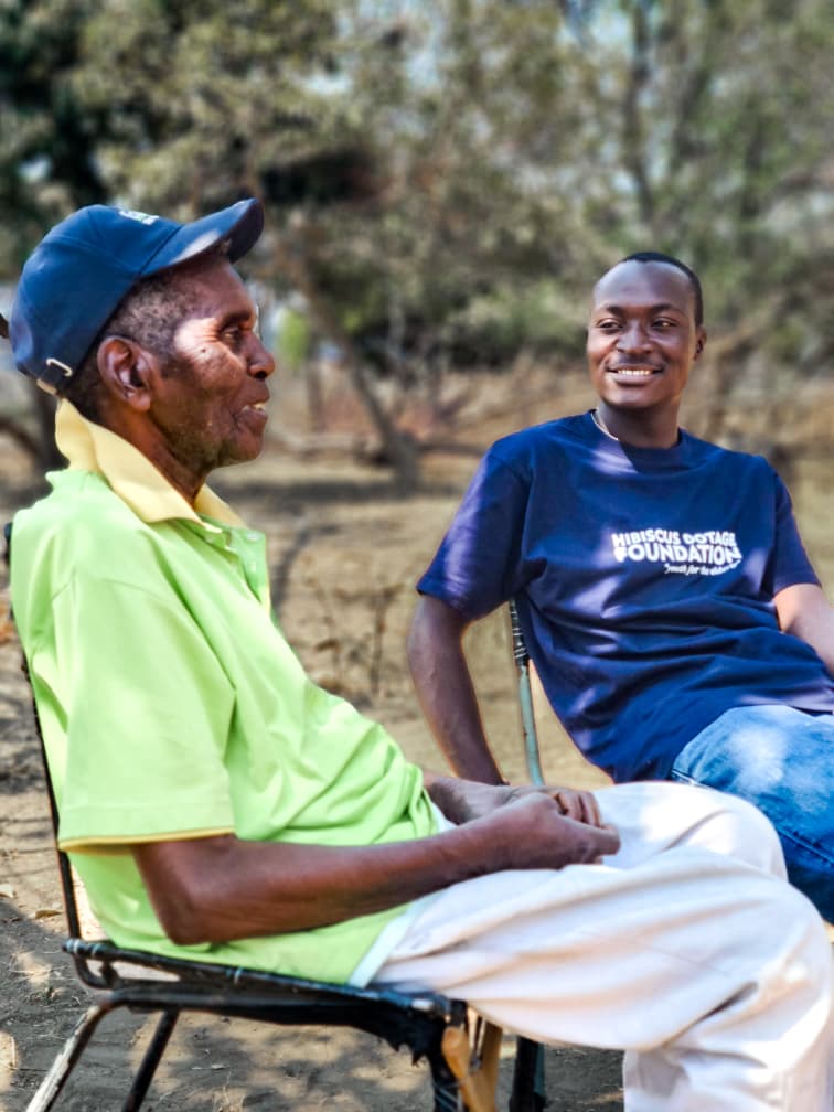 A young volunteer reading with a smiling elder